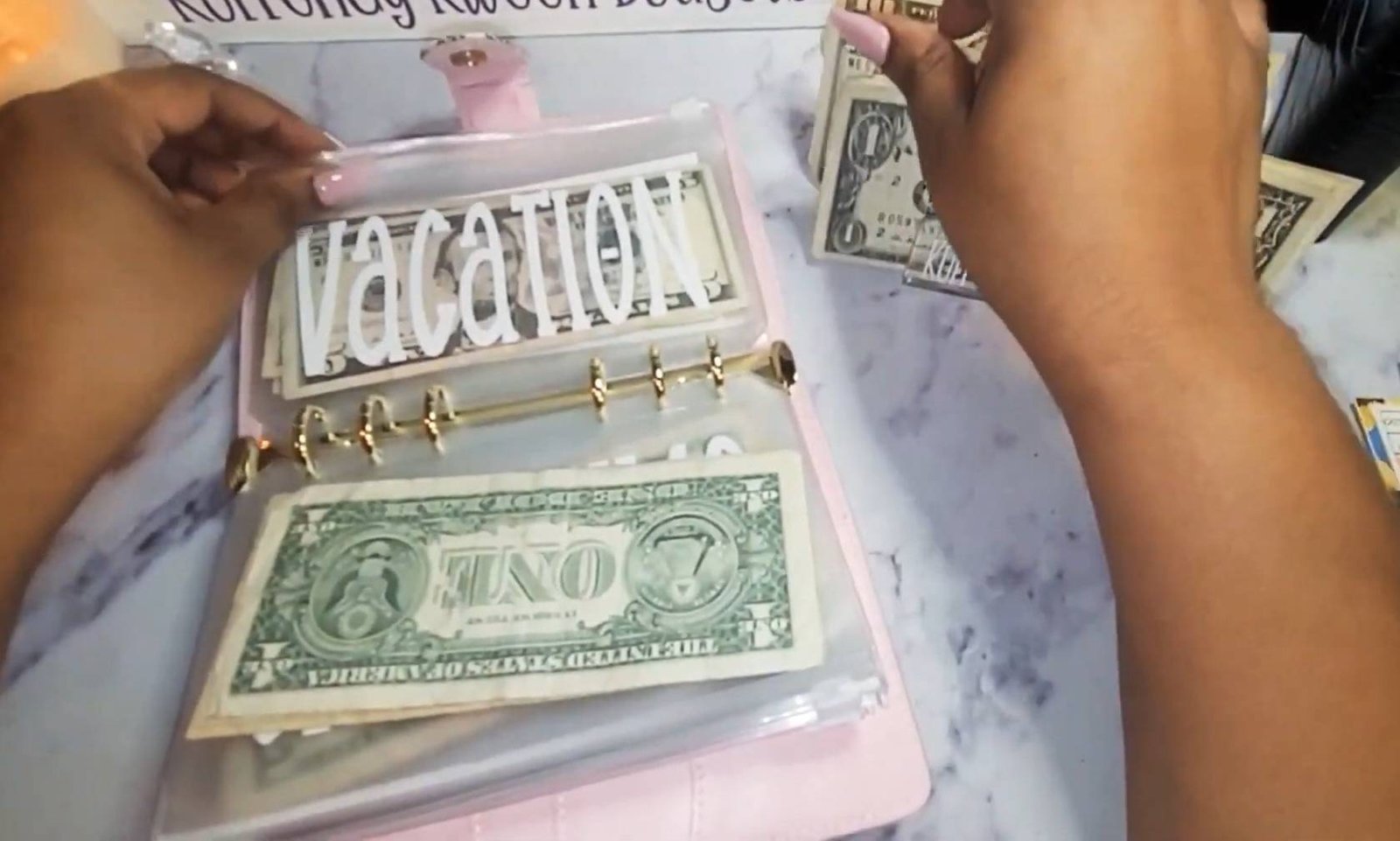 Hands tucking dollar bills into a labeled cash envelope in a budget binder.