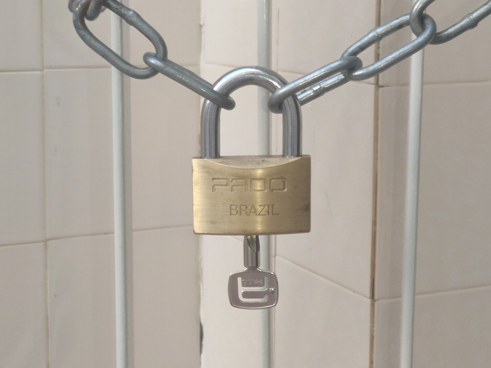 A brass padlock fastening a metal chain.