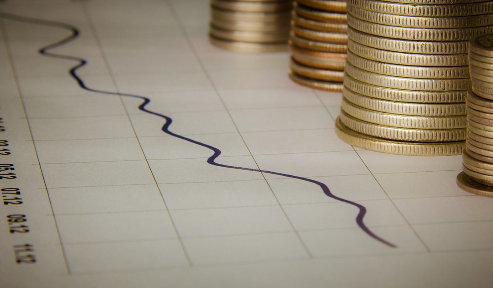 Stacks of coins rising beside a hand-drawn investment chart on graph paper.