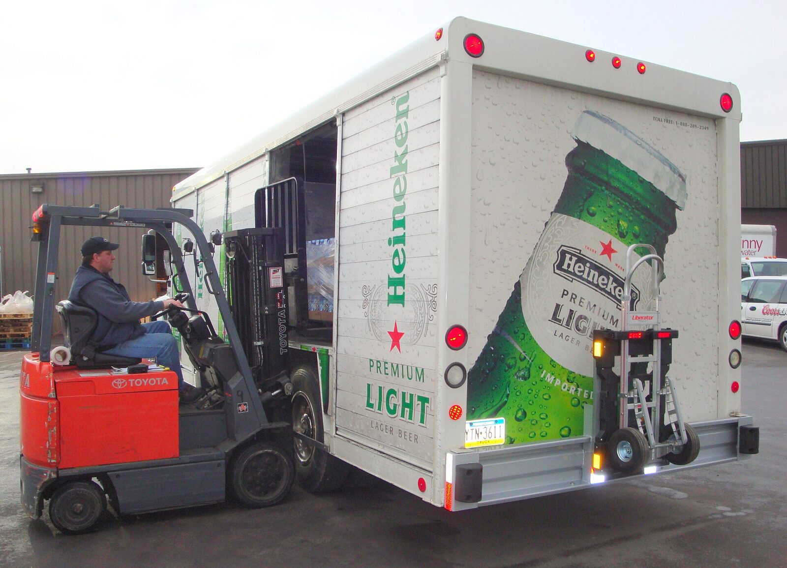 A forklift unloading cases from a beverage distributor's delivery truck at a warehouse