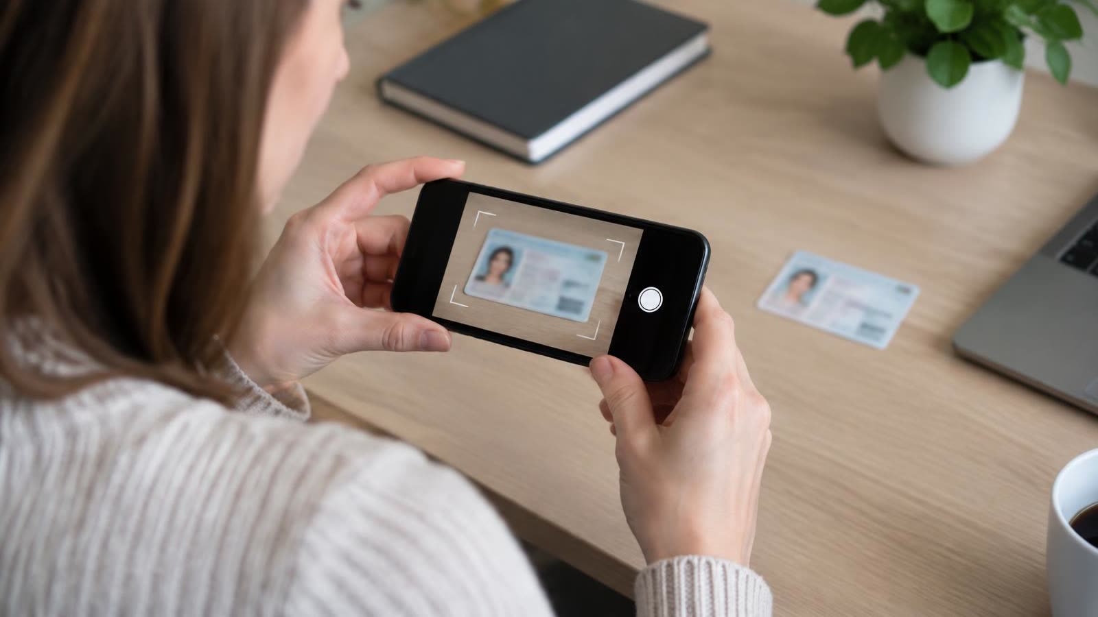 A woman photographing her ID card with her phone to verify her identity