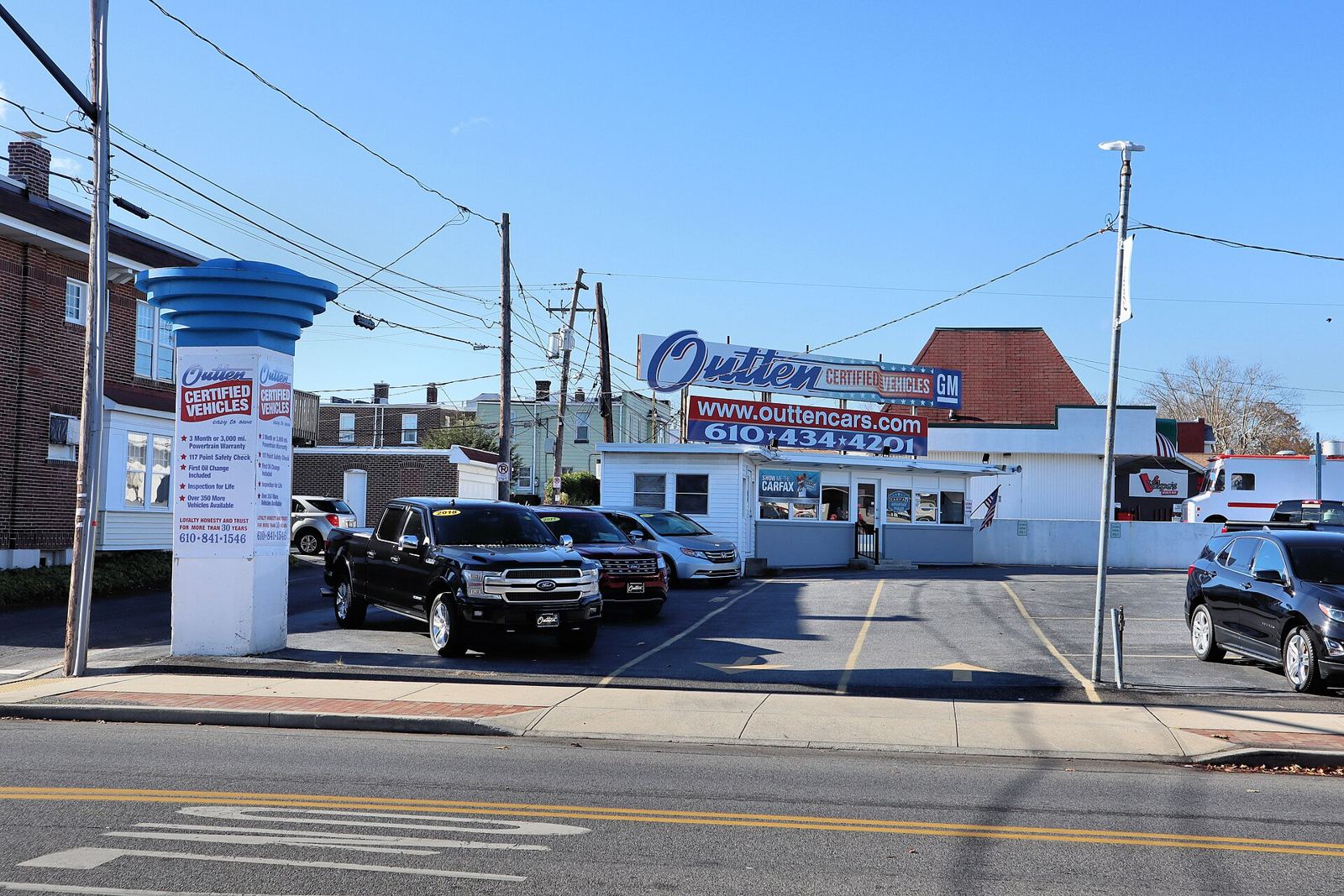 Pickup trucks and cars parked on a used car dealership lot.
