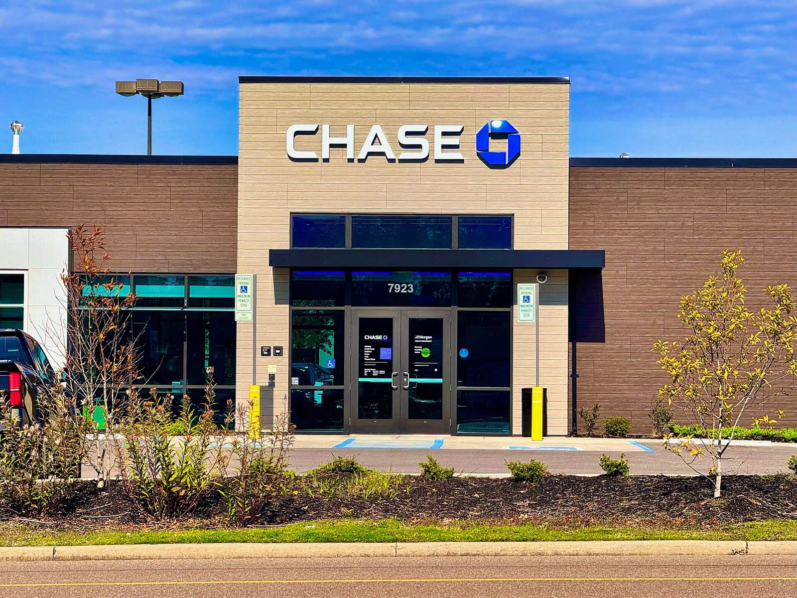 The entrance of a bank branch under a clear blue sky.