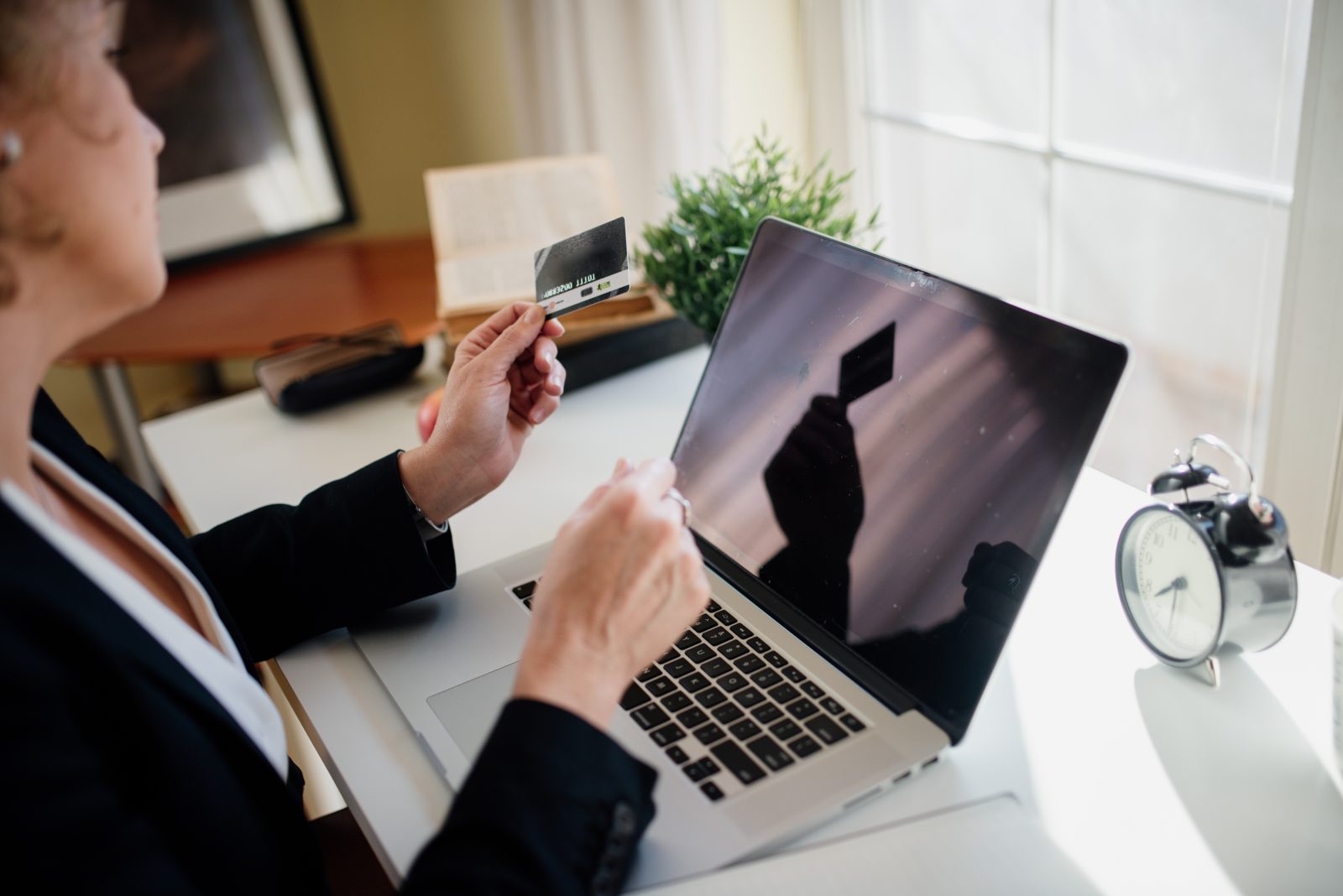 A person holding a credit card while paying bills on a laptop