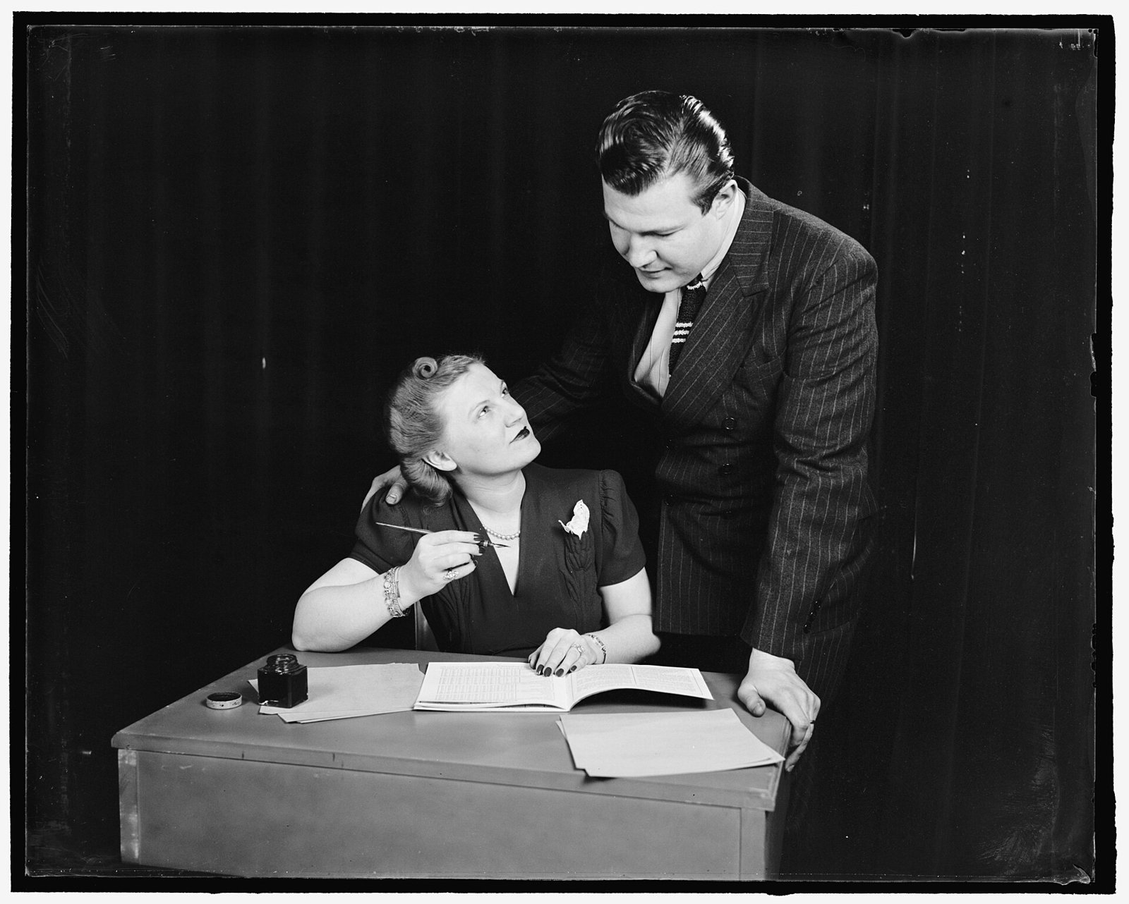 A vintage photo of a couple going over a budget book together at a desk.