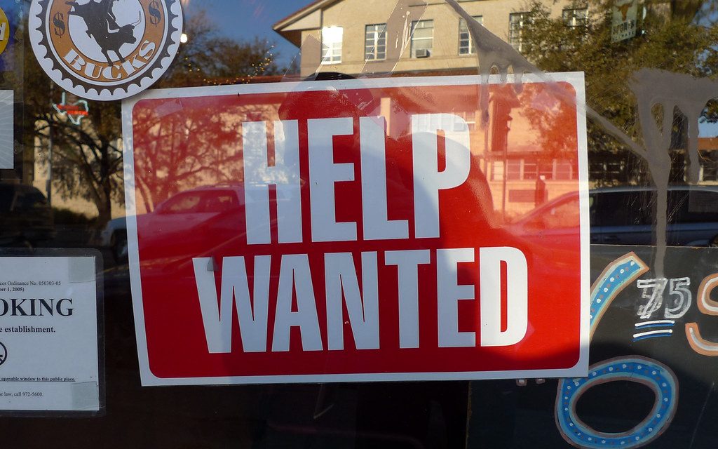 A Help Wanted sign in a shop window