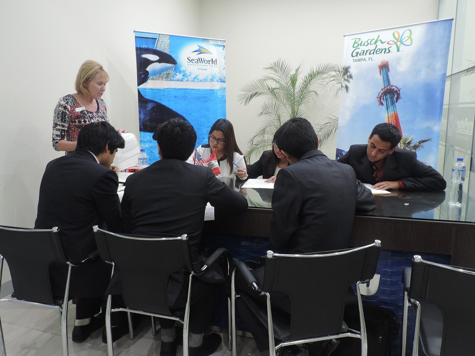 Job seekers sit at a table filling out applications during a hiring interview event.