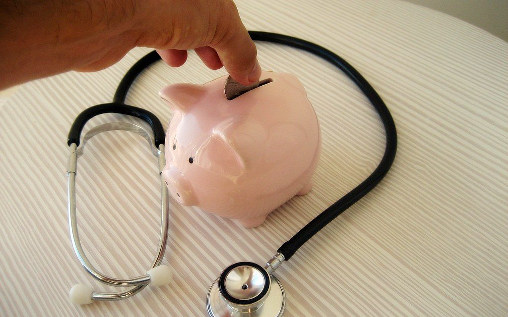 A stethoscope beside a piggy bank