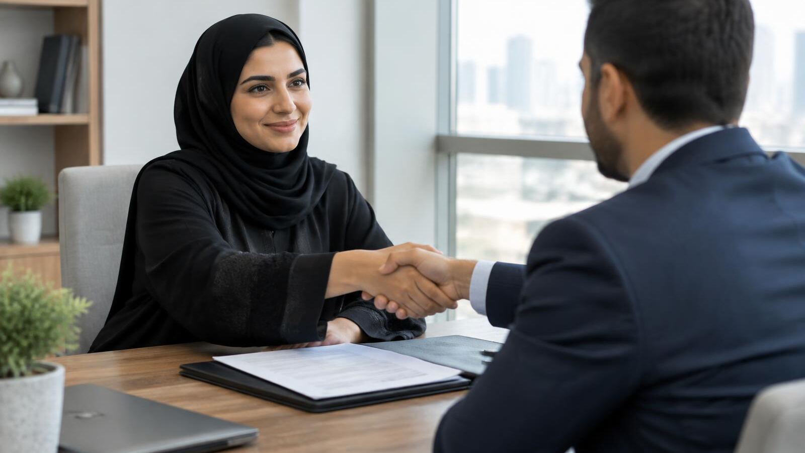 Homebuyer shaking hands with a lender across a desk with financial documents