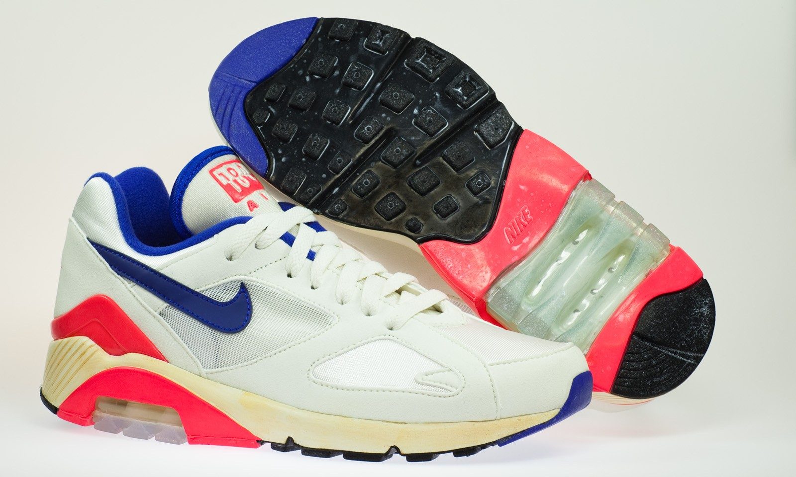 A pair of Nike Air Max 180 sneakers, one turned to show the sole.