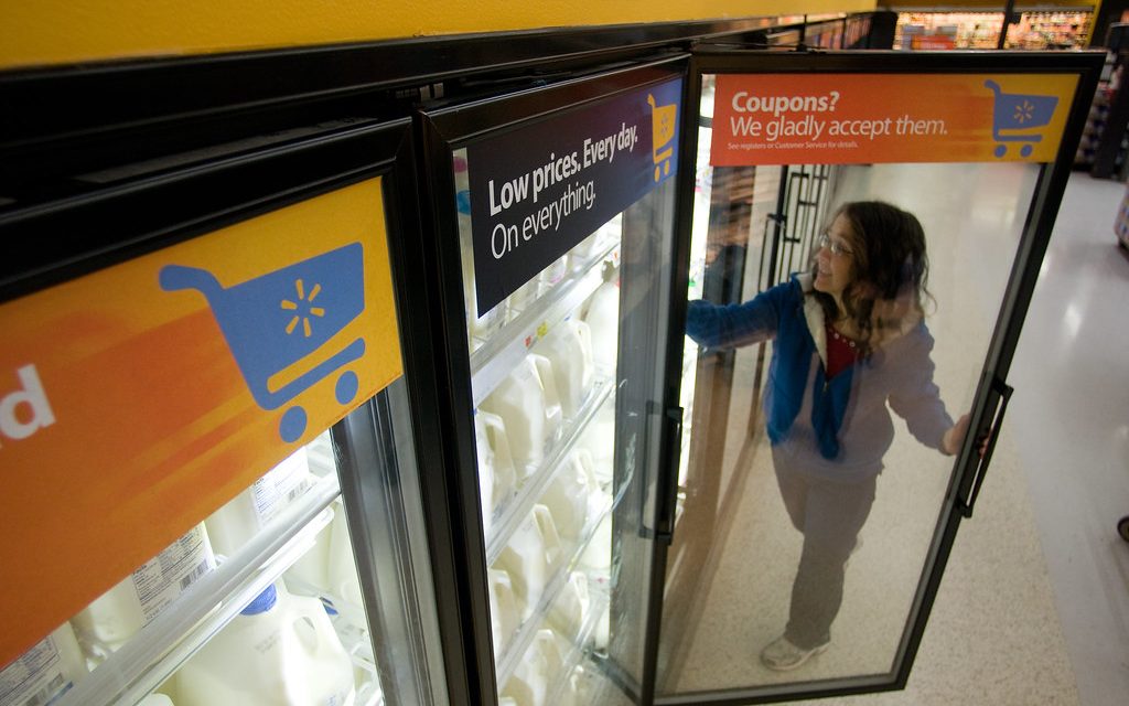 A shopper choosing milk in a grocery store