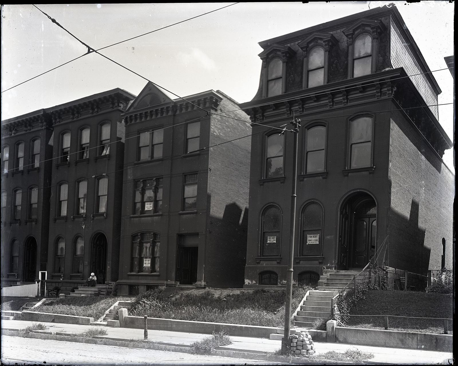 A vintage street of brick row houses with "For Rent" signs.