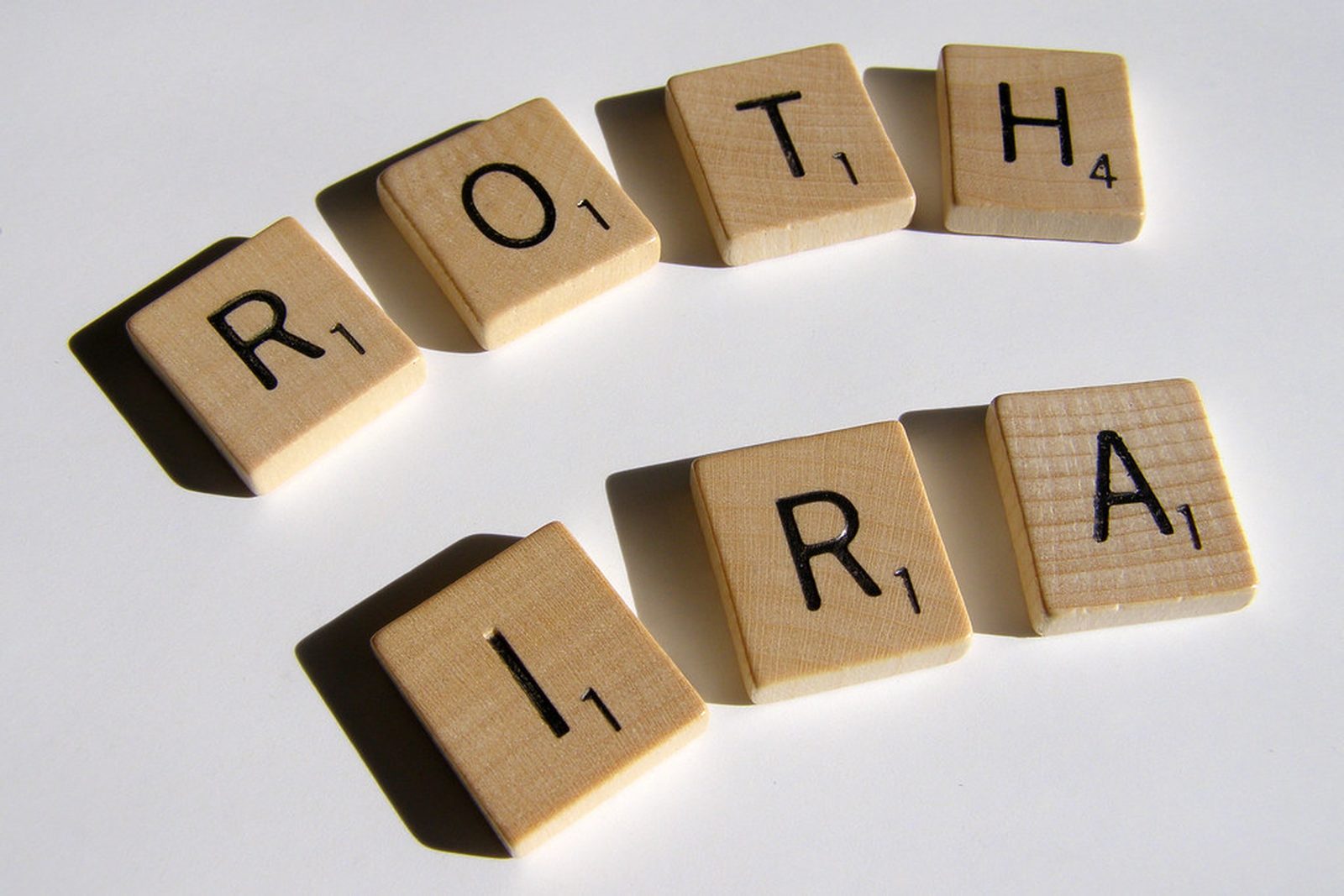 Wooden letter tiles spelling out Roth IRA on a white table.