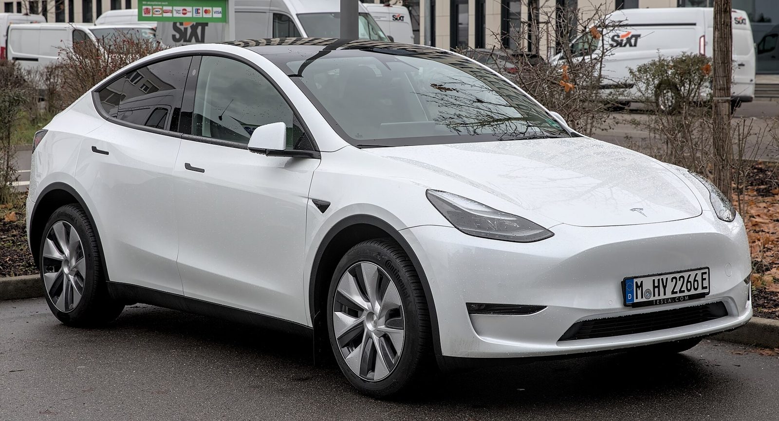 A white Tesla Model Y parked on a city street.