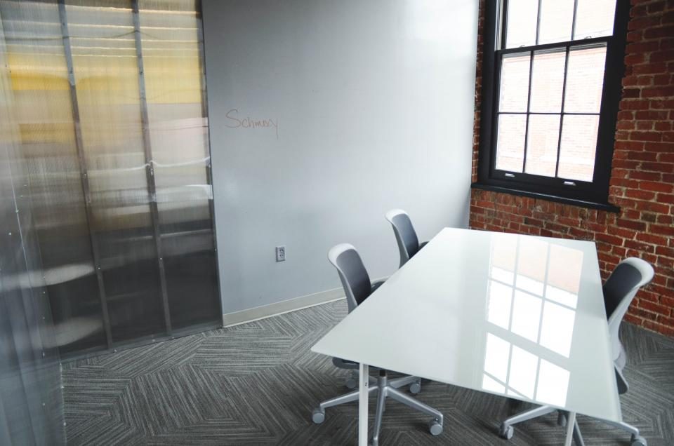 An empty startup meeting room with a white table and brick walls