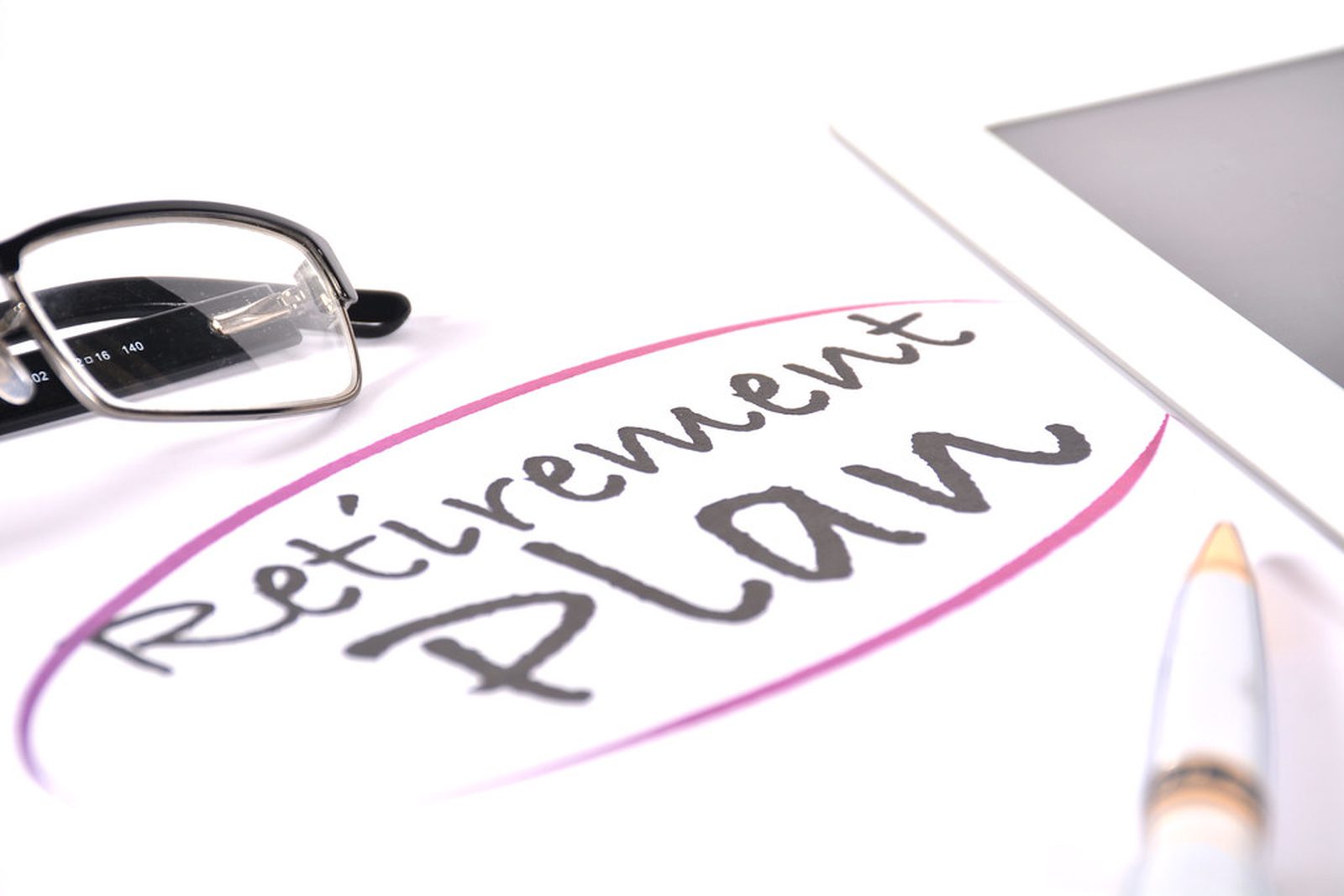 The words Retirement Plan circled on paper beside reading glasses and a pen.