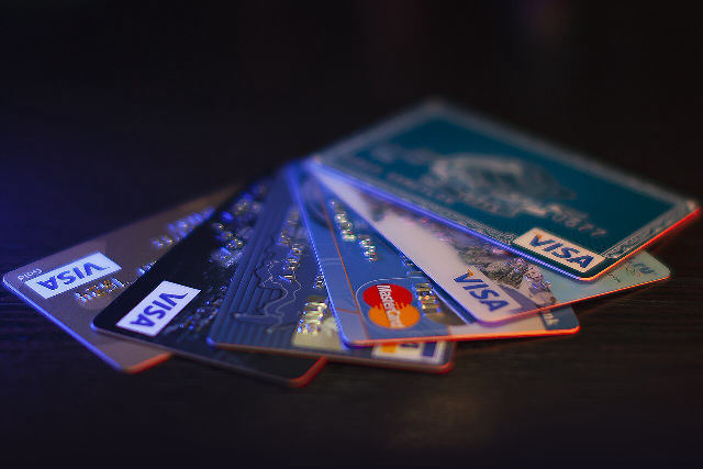 A fanned-out stack of Visa and Mastercard credit cards on a dark table