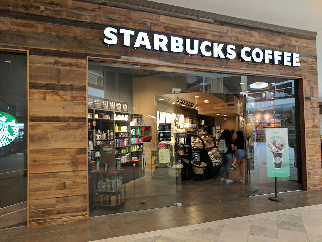 A Starbucks Coffee store with the Starbucks sign and logo inside a shopping mall