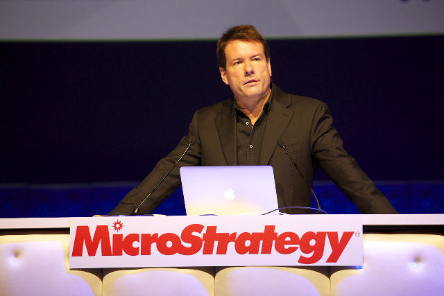 Strategy executive chairman Michael Saylor speaking at a podium with the MicroStrategy name on the front